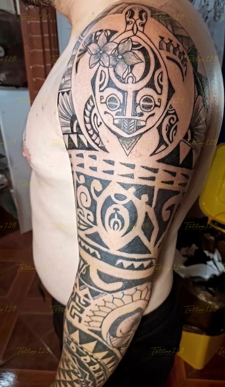 Tatuaje de media manga polinesia en el brazo que incorpora el diseño tradicional de una tortuga y flores de tiaré, en estilo de polinesios y tribales, realizado en el estudio Tattoo120 en Colina, Región Metropolitana.